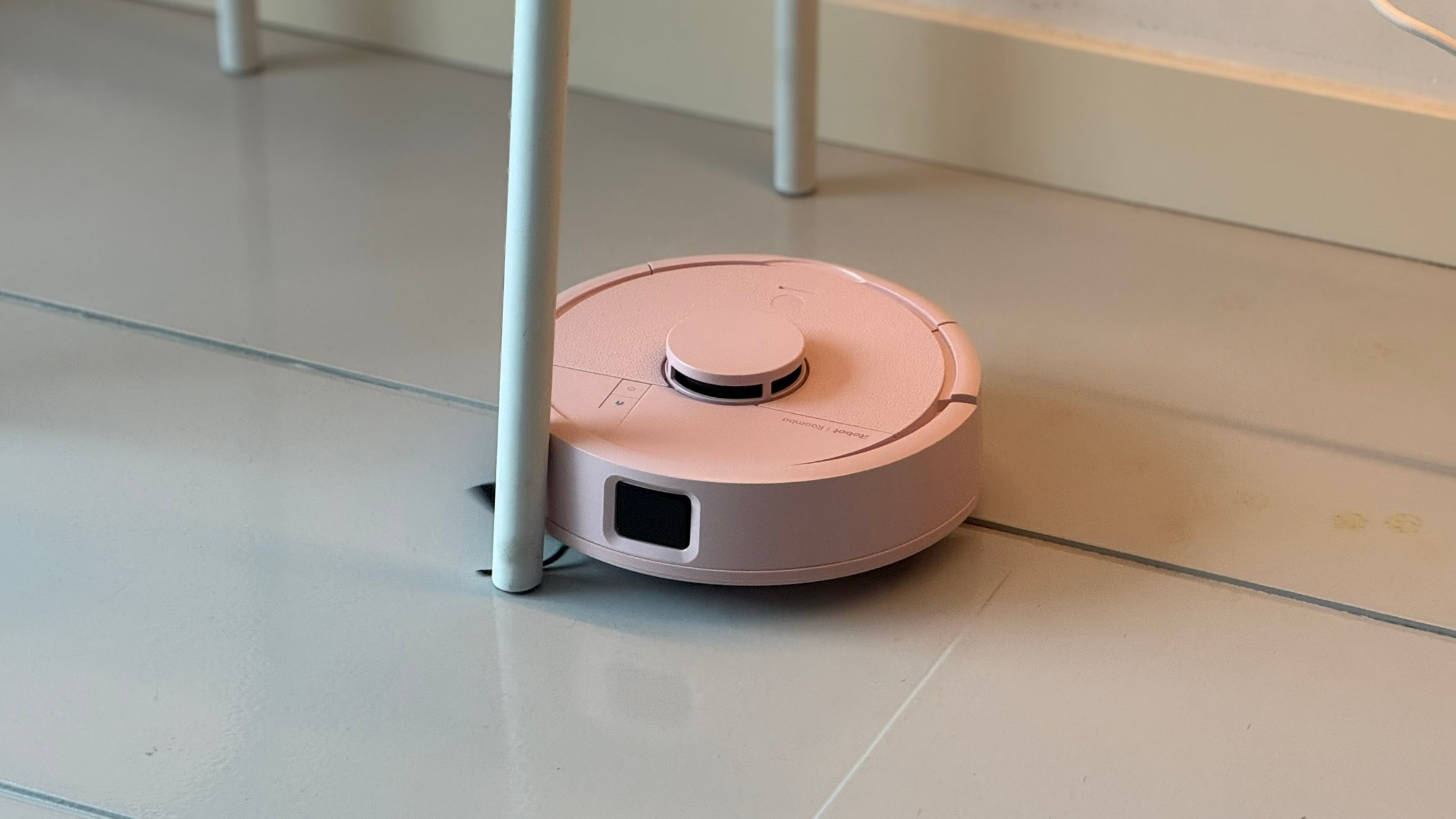 El dispositivo apurando la limpieza al lado de una pata de la mesa