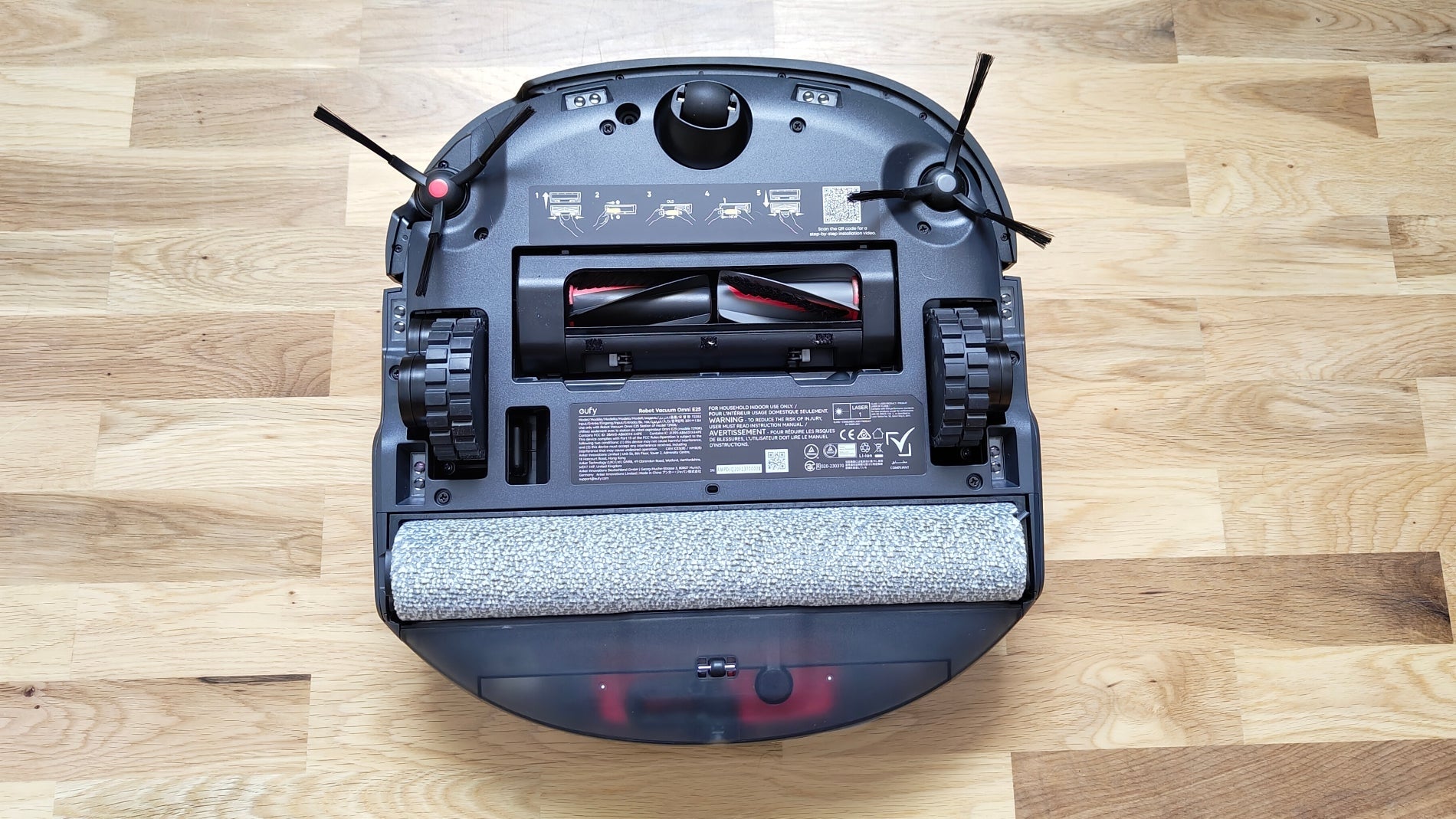 La parte inferior del Eufy Omni E25 con las tres ruedas, el cepillo "DuoSpiral", el cepillo de fregado y los dos cepillos laterales / Fotografía de David Freire