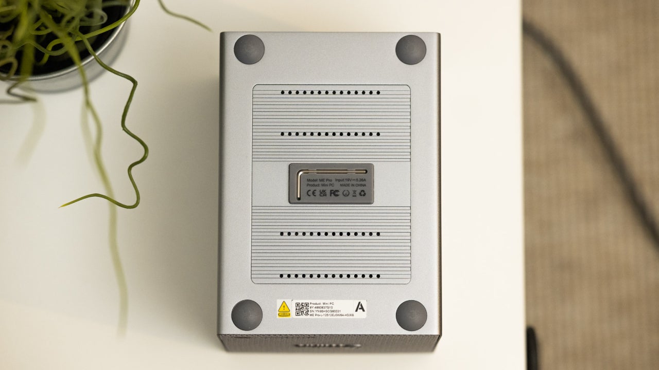 En la parte inferior del Beelink ME Pro encontrarás una pieza plástica con una herramienta para extraer las bandeja de los discos HDD y para acceder a las ranuras de los discos NVME / Fotografía: Elisa Piñón