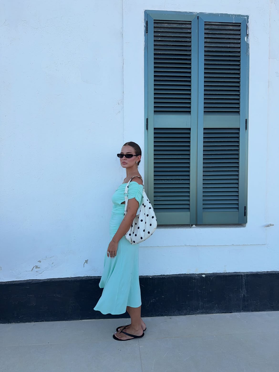 El bolso de lunares y las sandalias negras completan el look turquesa de la influencer | @lauraescanes