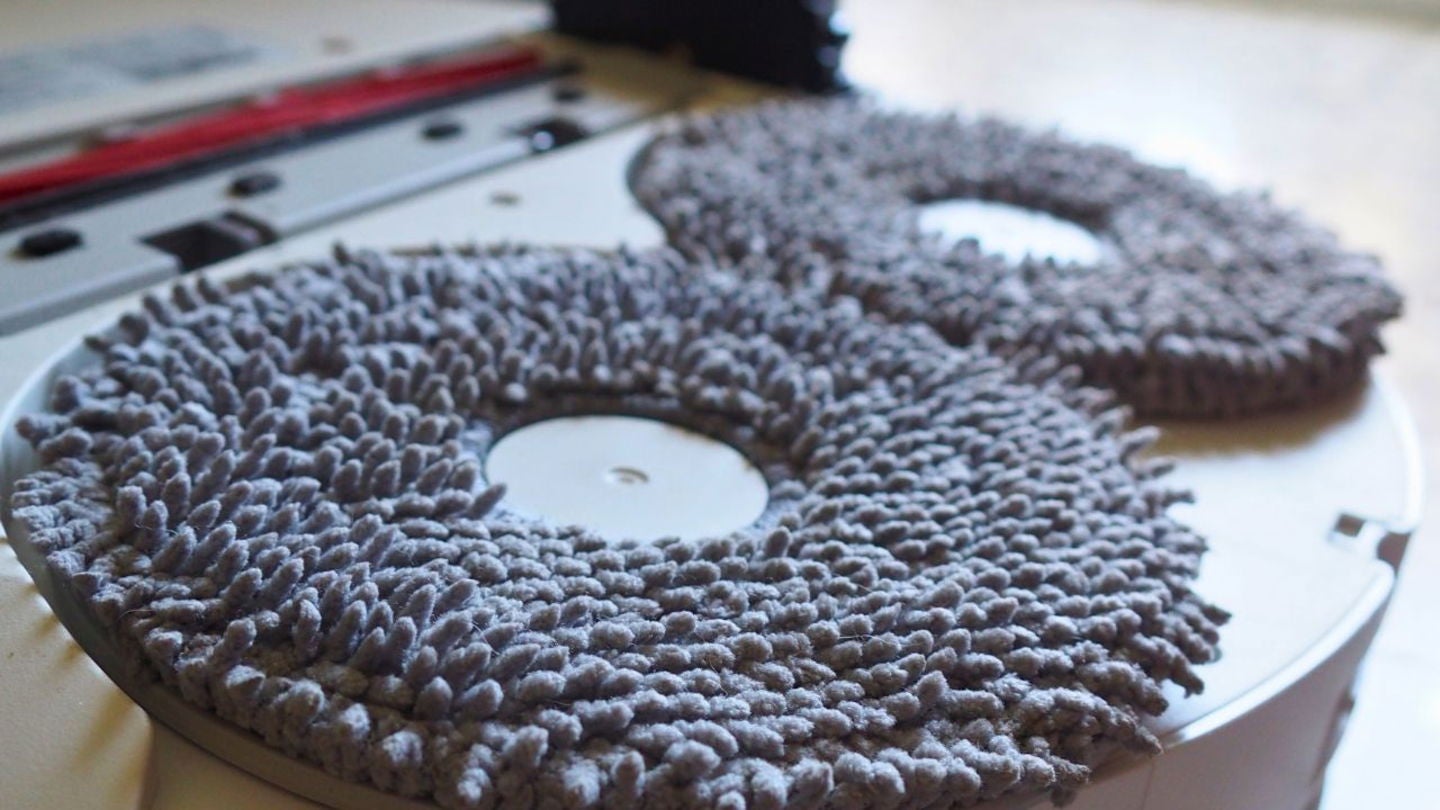 La parte inferior del robot aspirador de Roborock. Las mopas son extraíbles; la pieza roja es el rodillo de goma. El desplazamiento del dispositivo por el suelo es muy fluido gracias a sus ruedas de calidad | Imagen de Jesús Quesada