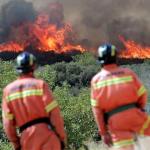 Dos bomberos observan las llamas cerca de la localidad de Sumacarcer (Valencia)