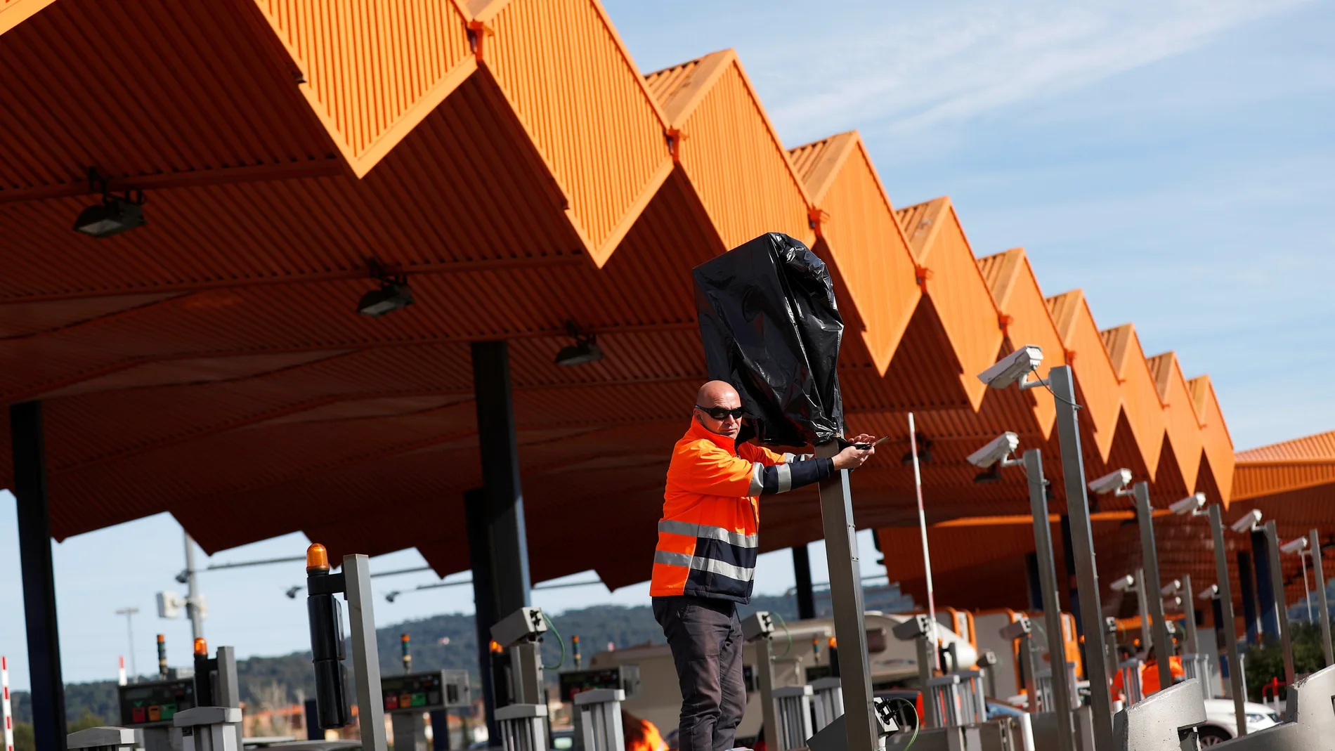 Operarios de autopistas trabajan en quitar las bolsas en las cámaras del peaje de la autopista AP-7