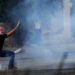 Un manifestante palestino se protege del gas lacrimógeno lanzado por las tropas israelíes cerca del asentamiento judío de Beit El, cerca de Ramala