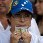 Una mujer sostiene su identificación para firmar la petición de un referéndum revocatorio contra Nicolás Maduro.