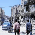 Varios civiles caminan por las calles de la devastada ciudad de Duma