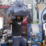 Un comerciante camina cargado con sus mercancías por una céntrica calle de Atenas