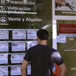 Una persona lee anuncios de venta de pisos en una agencia inmobiliaria