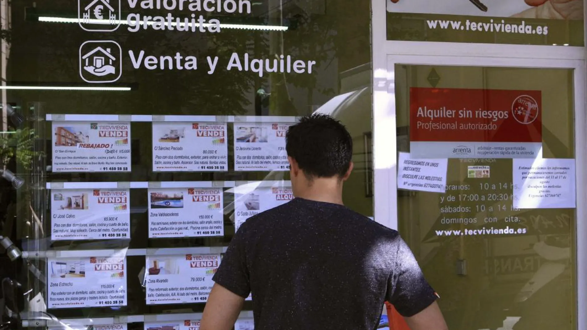 Una persona lee anuncios de venta de pisos en una agencia inmobiliaria
