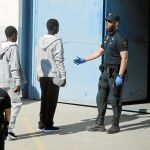 Inmigrantes que llegaron ayer en el Open Arms entran en una nave habilitada para ellos en el Muelle de San Roque en Cádiz