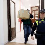 Un agente de la Guardia Civil lleva una caja con el material incautado en el registro de las oficinas del grupo municipal popular.