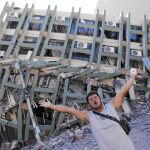Un vecino de Portoviejo hace gestos en petición de ayuda frente a uno de los edificios desplomados por el seísmo