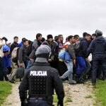 Un agente de policía observa a los refugiados procedentes de Croacia mientras caminan hacia el centro de registro de Brezice, Eslovenia