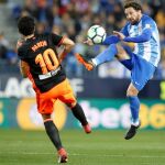 El centrocampista del Valencia CF Daniel Parejo (i) intenta robarle el balón al centrocampista del Málaga Manuel Iturra