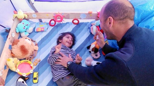 El pequeño Osman juega con uno de los bomberos españoles que montan guardia las 24 horas del día para que no pierda la vida