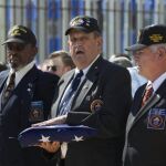 Los exmarines estadounidenses Larry Morris (d), James Tracy (c) y Mike East (i), encargados de arriar la bandera de EE.UU. hace 54 años en la isla, la sostienen durante la ceremonia de izado