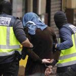 Dos policías acompañan a un presunto yihadista detenido en Madrid, acusado de formar parte de un grupo vinculado al Estado Islámico.
