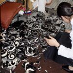 Una mujer recoge vajillas rotas de un restaurante Kumamoto tras el seísmo
