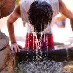 Un joven se refresca en una fuente del Patio de los Naranjos de la Mezquita Catedral de Córdoba.