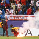 Un operario retira una bengala del terreno de juego durante el partido entre el Atlético de Madrid y el Benfica