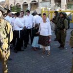 Soldados israelíes bloquean una calle a palestinos que esperan mientras colonos judíos caminan alrededor del mercado palestino en la ciudad cisjordana de Hebrón