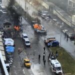 Varios vehículos envueltos en llamas mientras agentes de policía asisten a los heridos después de que explotara un coche bomba frente al Palacio de Justicia de Esmirna