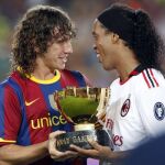 El capitán del FC Barcelona, Carles Puyol (i) entrega el trofeo conseguido al delantero brasileño del AC. Milan, Ronaldinho Gaucho, tras el partido, correspondiente a la edición 45 del trofeo Joan Gamper