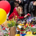 Una mujer enciende una vela en recuerdo de las víctimas en la Plaza de la Bolsa de Bruselas