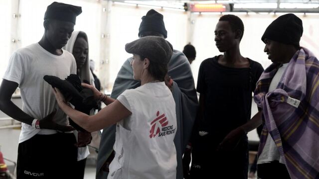Un inmigrante recibe ropa de un tripulante del Aquarius