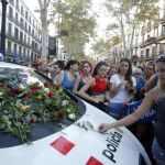 Un grupo de personas depositan rosas en el parabrisas de un coche policial tras los atentados de Barcelona