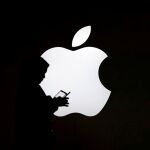 Un hombre consulta su móvil en una feria de Apple