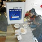 Varias personas toman el desayuno en un habitáculo de un bar diseñado para la gente fumadora