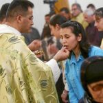 Una católica iraquí acude a comulgar en una parroquia de Bagdad, donde todas las celebraciones navideñas serán diurnas