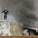 Bomberos trabajan en las labores de extinción de varios edificios en llamas tras estrellarse una avioneta junto a un supermercado en Tires cerca de Estoril
