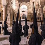 Nazarenos de una de las cofradías de Córdoba que procesionó ayer pasa por la catedral durante la realización de su estación de penitencia