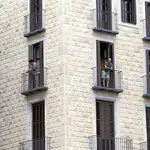 Unos turistas en los balcones de un edificio de apartamentos con vistas a la plaza Sant Jaume