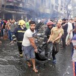 Varios iraquíes trasladan a las víctimas en mantas tras la explosión en el mercado de Karrada, en Bagdad