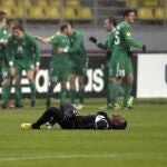 El jugador del levante, Papa Diop, tumbado en el cesped, mientras los jugadores del Rubin celebran la victoria