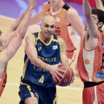 El base del Herbalife Gran Canaria Albert Oliver (c) entra a canasta entre Guillem Vives (d) y Justin Hamilton (i), del Valencia Basket