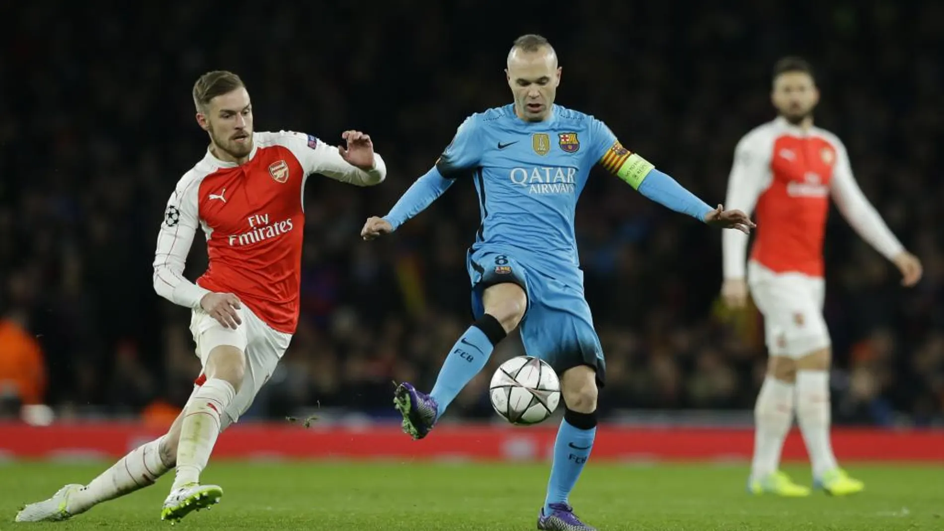 Aaron Ramsey pelea por el balón con Andrés Iniesta