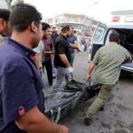 Varios trabajadores retiran el cuerpo de una de las víctimas del ataque suicida de ayer
