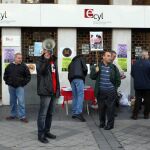 Un grupo de personas mayores paradas se manifiestan a las puertas de una oficina de empleo