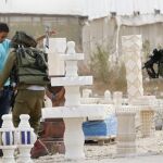 Un soldado israelí cachea a un joven palestino tras el ataque