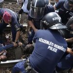 Unos refugiados son detenidos cuando trataban de subir a un tren en Hungría.