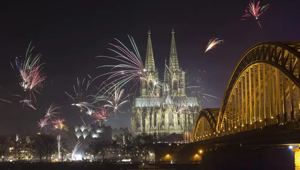 Fuegos artificiales iluminan la catedral de Colonia (Alemania) junto al río Rin durante las celebraciones de Año Nuevo