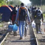 Refugiados caminan junto a las vías del tren en la frontera entre Serbia y Hungría.