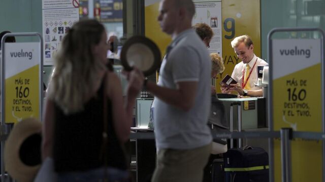 Personal de facturación de Vueling atiende a los viajeros en el Aeropuerto de El Prat.