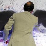 El presidente del Gobierno, Mariano Rajoy, ayer en Bilbao, escribe en el mural de Miguel Ángel Blanco en la escuela de verano de NNGG del PP