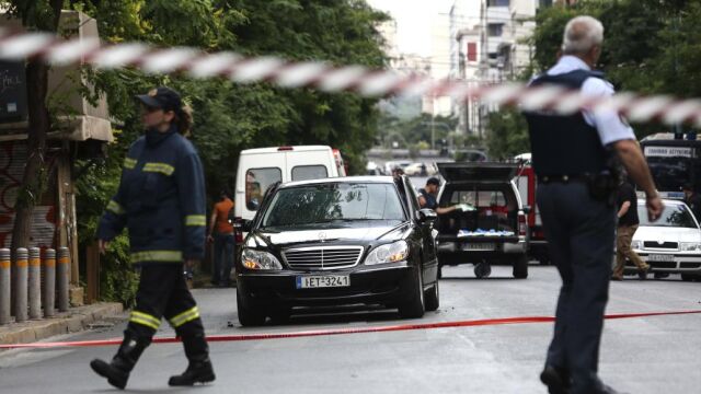 Miembros de los servicios de emergencias junto al coche del ex primer ministro griego Lucas Papademos.