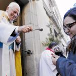 El padre Ángel bendice a un animal en la puerta de la iglesia de San Antón ante la atenta mirada de su dueña